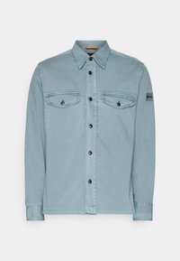 Chemise bleu clair à manches longues boutonnée avec deux poches poitrine et un petit patch "BOSS" sur la manche supérieure gauche.