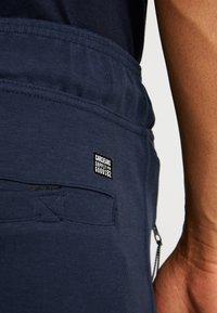 Marine joggers met een gestructureerde stof, elastische tailleband en een zijzak met rits en een merklabel.