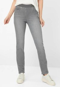 Szare dżinsy o dopasowanym kroju, z elastycznym paskiem w talii, przednimi kieszeniami i gładką teksturą. W połączeniu z białymi sneakersami.