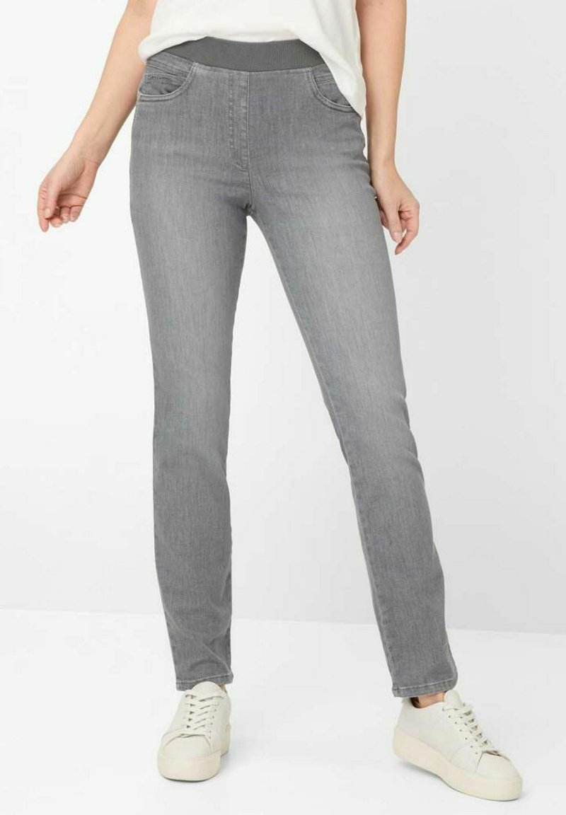 Szare dżinsy o dopasowanym kroju, z elastycznym paskiem w talii, przednimi kieszeniami i gładką teksturą. W połączeniu z białymi sneakersami.