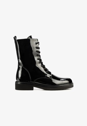 Botas de tobillo de charol negro con punta redondeada, cierre de cordones en la parte delantera y herrajes negros. Presenta una suela gruesa y textura suave.