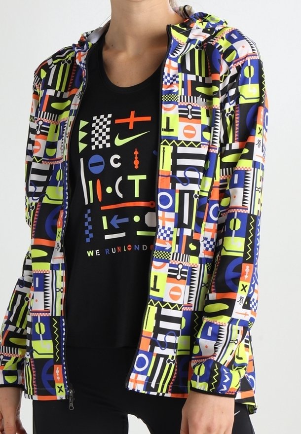 Personne portant une veste colorée à motif géométrique sur un t-shirt noir avec des symboles abstraits multicolores et le texte "WE RUN LONDON".