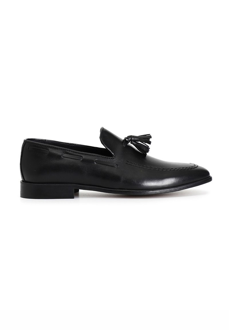 Schwarze Leder Slipper mit einem Quasten-Design, glatter Textur, flacher Sohle und einer eleganten, spitzen Zehenform.
