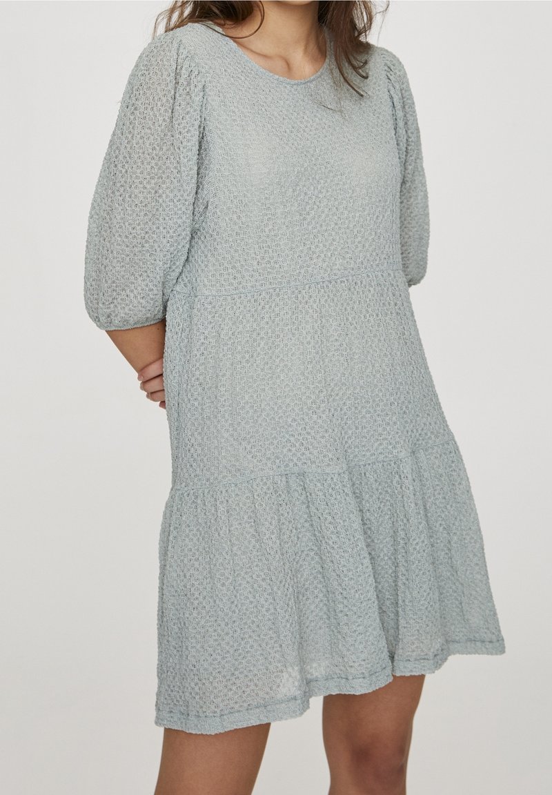 Vestido de algodón texturizado en azul claro, con mangas cortas abullonadas, cintura fruncida y falda acampanada que llega hasta la mitad del muslo.