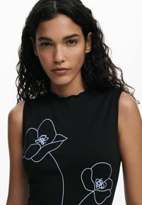 Top negru fără mâneci, cu broderie florală albă, având un decolteu cu margine ondulată și un design ajustat care se conturează pe trup.