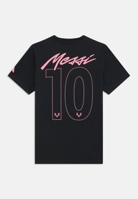 Černé tričko s krátkým rukávem s nápisem "Messi" a číslem 10 ve velkém růžovém písmu na zadní straně, s jemnými logy uvnitř čísel.