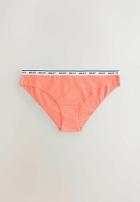 Culottes pour femmes de couleur corail avec une ceinture élastique blanche comportant en motif répété le texte noir "NEXT" sur un fond gris clair.