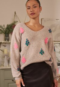 Ljusbrun stickad tröja med V-ringning, prydd med färgglada trädesigns i rosa och grönt, samt texturerade pom-pom detaljer genom hela plagget.