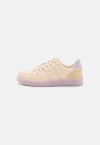 Zapatillas beige con un upper de cuero suave, sutiles acentos lilas, dos rayas decorativas y una suela de goma transparente. Diseño de perfil bajo.