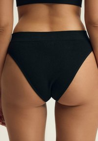 Czarna, prążkowana bielizna hipster z szerokim pasem, bezszwowe brzegi i gładka tekstura, z wysoki wycięciem nogawki.