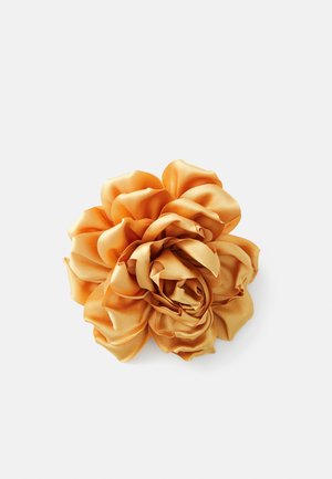 Golden satin fabric scrunchie with a ruffled rose shape on a white background.