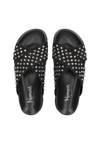 Schwarze Rutsch-Sandalen mit überkreuzten Riemen, verziert mit silbernen Nieten. Glattes Lederinterieur, flache Sohle und keine sichtbare Ferse.