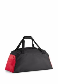 Sort duffelbag med røde detaljer, lavet af slidstærkt stof. Har dobbelt håndtag og et rummeligt hovedrum. Tekstureret sidelomme.
