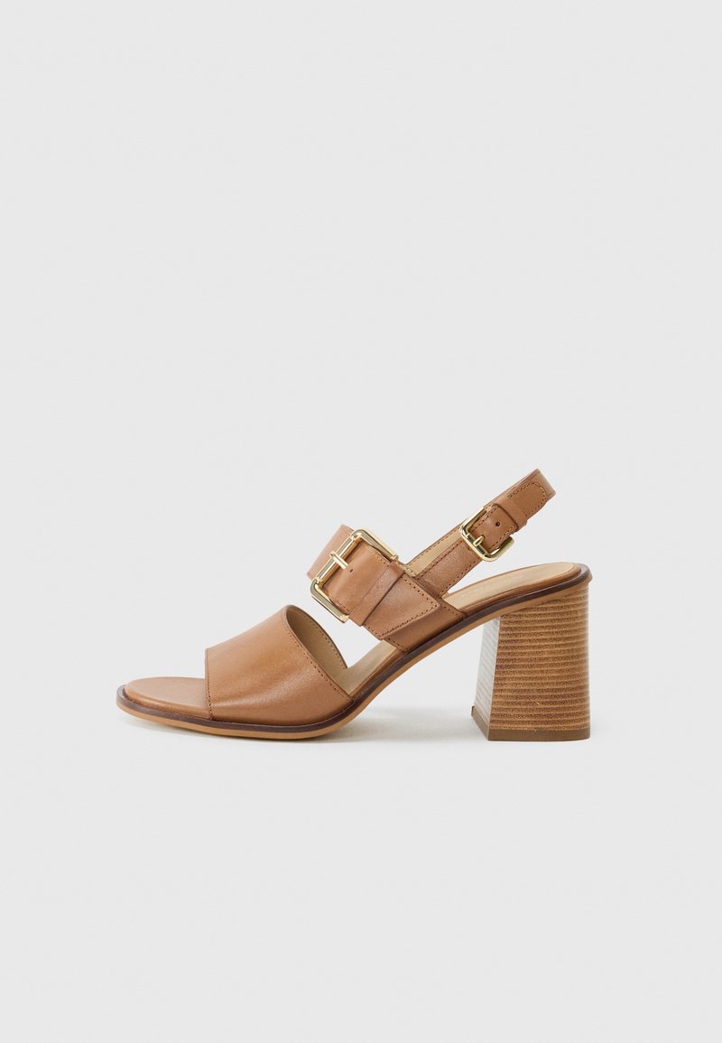 Bruna läderklackar med en bred framrem, justerbar vristrem med ett guldspänne och en texturerad blockklack.