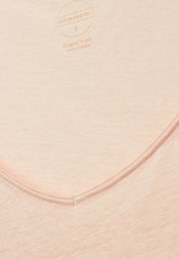 Ljusrosa topp i mjukt tyg med V-ringning och ren sömnad, samt en etikett som läser "Intimissimi, designad i Italien, S."