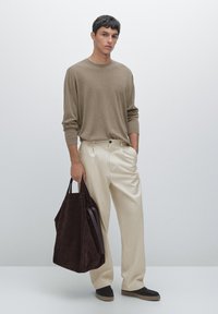 Beige långärmad skjorta, krämfärgade byxor och mörkbrun mocka tote-väska. Bruna skor med låg profil. Minimalistisk design, slät textur.