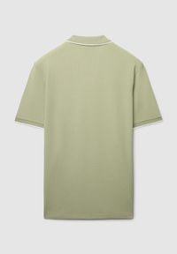 Polo in verde chiaro con tessuto a trama. Presenta un colletto classico e una finitura bianca a contrasto lungo il colletto e le maniche.