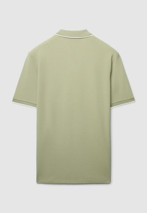 Polo vert clair en tissu texturé. Il présente un col classique avec une bordure blanche en accent sur le col et les manches.