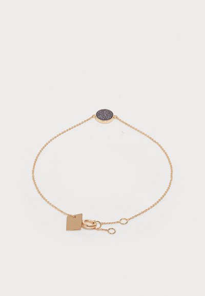 Zlatý náramok so zaobleným tmavým kameňom v strede, jemným reťazcom a štvorcovým príveskom s uzáverom.