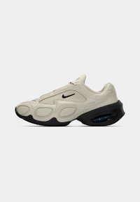 Μπέζ και μαύρο Nike sneaker με υφή στο επάνω μέρος, μαύρο λογότυπο swoosh και παχύ μαύρο σόλα με ορατή αερόσακο στη φτέρνα.