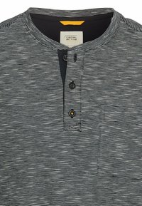 Czarny i biały paskowany t-shirt henley z zapięciem na guziki, krótkimi rękawami i jedną kieszenią na piersi. Miękka tkanina o luźnym kroju.