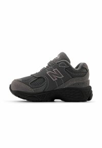 Scarpa sportiva grigia con pannelli in rete e dettagli in suede, caratterizzata da una suola in gomma robusta e dettagli cuciti. Logo classico di New Balance visibile.