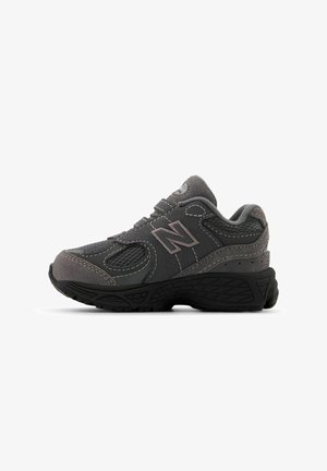 Chaussure de sport grise avec des panneaux en mesh et des accents en daim, dotée d'une semelle en caoutchouc robuste et de détails cousus. Logo New Balance classique visible.