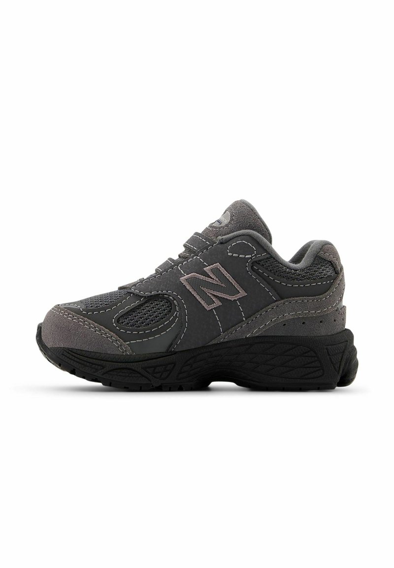 Scarpa sportiva grigia con pannelli in rete e dettagli in suede, caratterizzata da una suola in gomma robusta e dettagli cuciti. Logo classico di New Balance visibile.