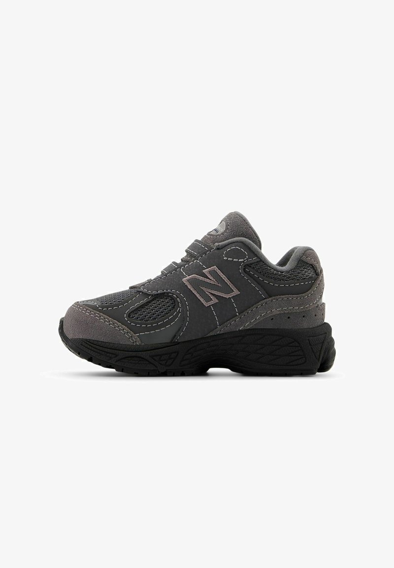 Grauer Sportschuh mit Mesh-Einsätzen und Wildleder-Akzenten, ausgestattet mit einer robusten Gummisohle und genähten Details. Klassisches New Balance-Logo sichtbar.