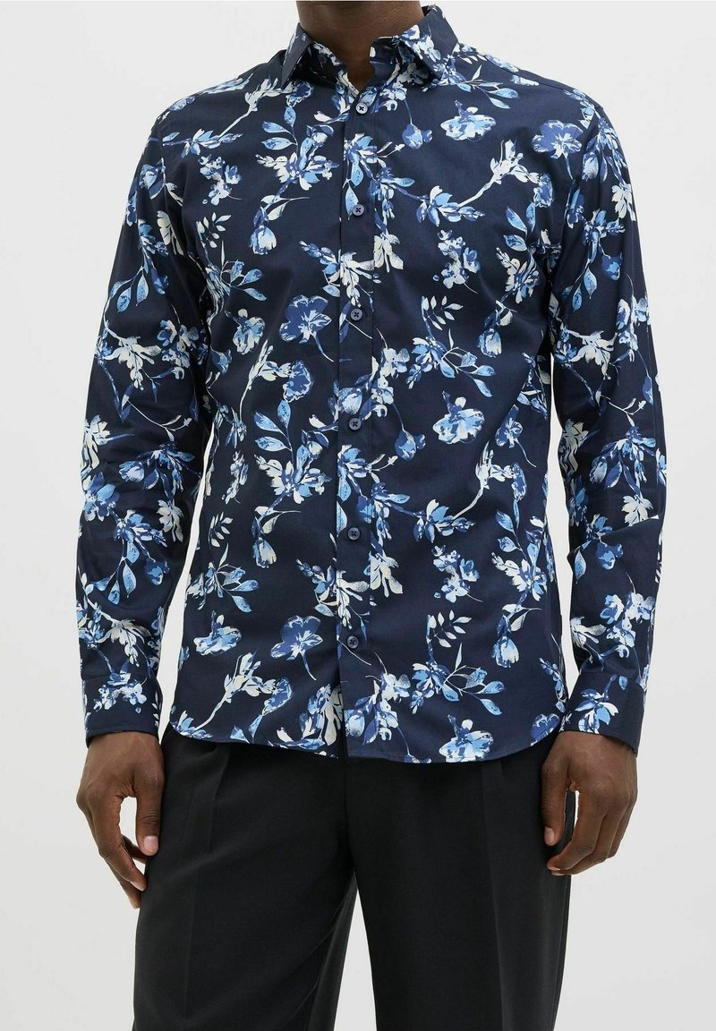 Camicia blu navy a fiori realizzata in tessuto leggero, caratterizzata da motivi floreali blu e bianchi, maniche lunghe e chiusura frontale con bottoni.