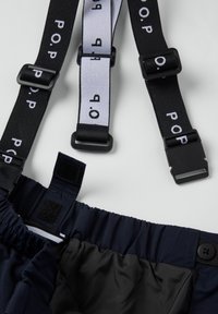 Marineblauwe shorts met een elastische tailleband en zwarte afneembare bretels met witte tekst. Inclusief een klittenbandsluiting en een knoopdetail.