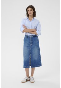 Denim midi-hame, jossa on etuventtiili, sininen pesu, korkea vyötärö, yhdistetty vaaleansiniseen raidalliseen nappipaitaan ja valkoisiin lenkkareihin.