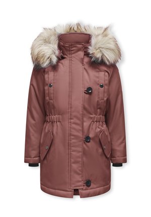 Barn iført mørkeblå parka med pelsluge, blå optrukne jeans, sorte støvler, stående mod hvid baggrund.