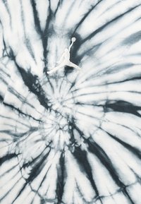 Ύφασμα tie-dye σε ασπρόμαυρο σπιράλ με λευκή σιλουέτα παίκτη μπάσκετ που πηδάει και φτάνει για τη μπάλα στο κέντρο.