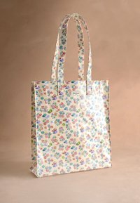 Krémová taška na rameno s dlhými rúčkami zdobená malými farebnými kvetinovými a ovocnými vzormi na béžovom pozadí.