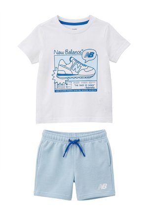 T-shirt bianca a maniche corte con grafica di sneaker blu e testo abbinata a pantaloncini azzurri chiari con coulisse e logo New Balance.