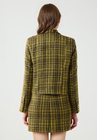 Geel en zwart geruit textuur blazer met lange mouwen, slim fit ontwerp en cropped lengte, gecombineerd met een bijpassende miniskirt.