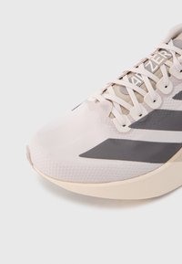 Buty do biegania z jasnoróżową siateczkową cholewką, szarymi akcentami i teksturowanym wykończeniem. Posiadają płaskie sznurowadła oraz amortyzowaną podeszwę.