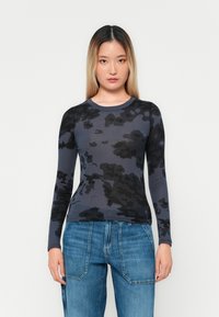 Camisa de mangas largas en gris oscuro con un patrón de camuflaje negro, hecha de tela suave; presenta un escote redondo y un diseño ajustado.