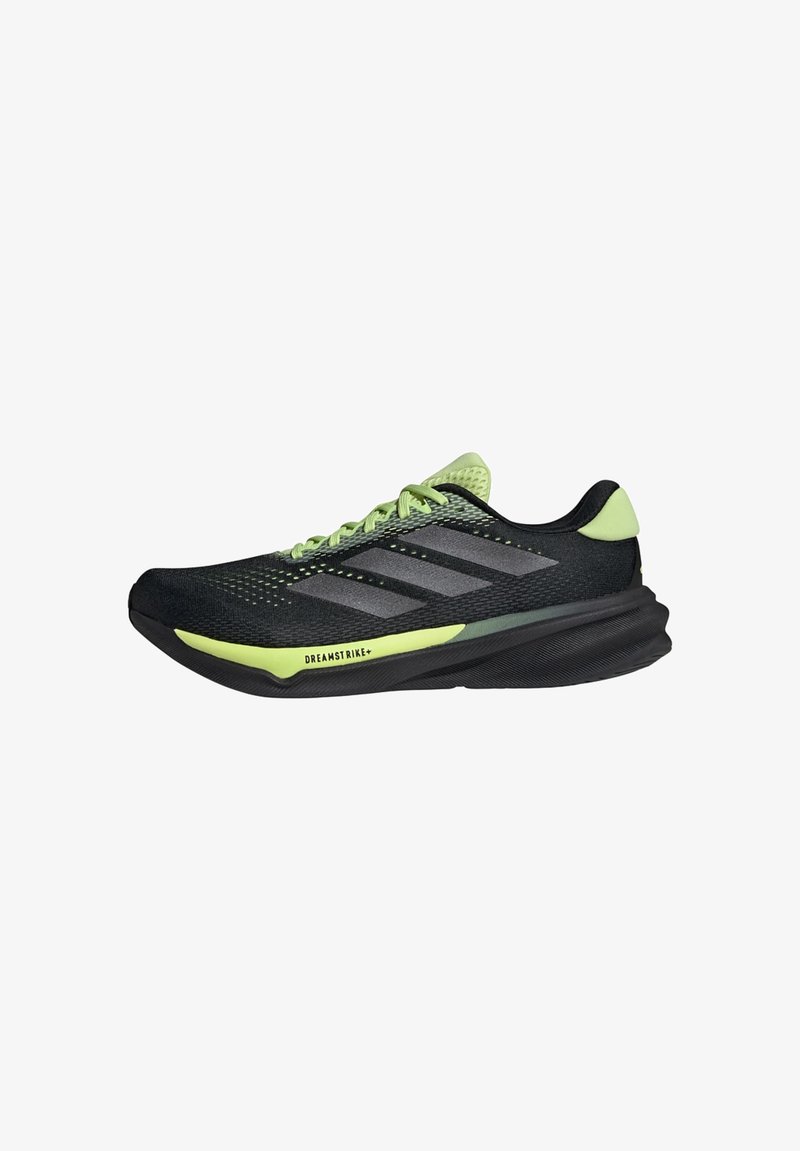 Black athletic shoes with green accents, mesh upper, and three gray stripes. Features a curved sole and a textured grip pattern.