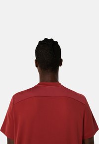 Červené sportovní tričko s texturovanou síťovanou horní částí a krátkými rukávy, vyrobené z hladkého materiálu a s kulatým výstřihem.