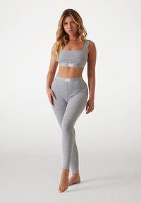 Gray ribbed crop top with thick straps paired with high-waisted leggings, both featuring textured fabric and logo accents at the waistband.