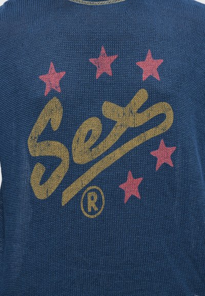 Μπλε πλεκτό πουλόβερ με υφή. Διαθέτει κίτρινο λογότυπο «Set» και ροζ αστέρια στην πλάτη. Στρογγυλή λαιμόκοψη και casual σχεδιασμό.