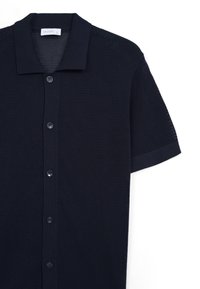 Polo shirt blu navy a maniche corte con texture in rete, colletto morbido e chiusura con sei bottoni, caratterizzato da un'etichetta del marchio discreta all'interno del colletto.