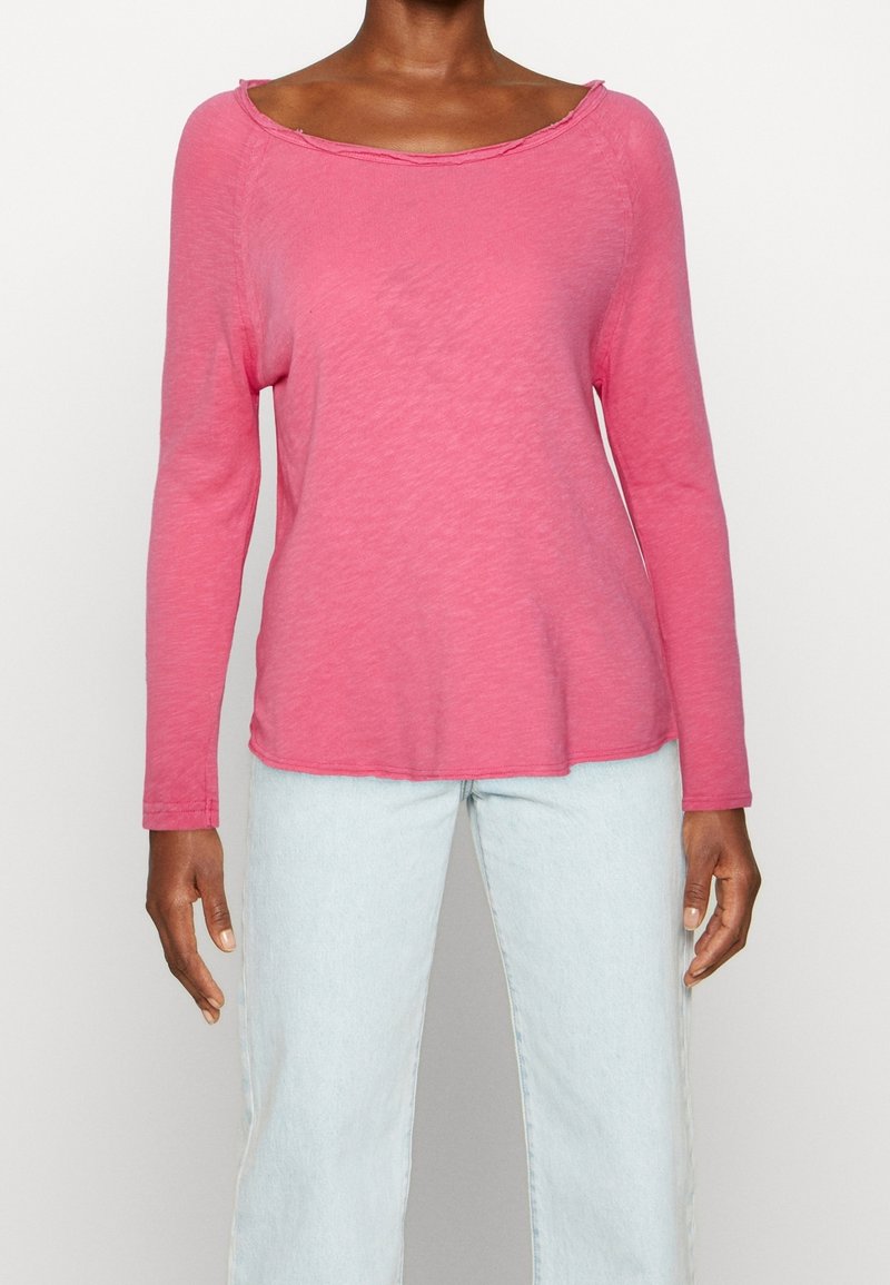 Long-sleeve, pink top with a wide neckline and a relaxed fit. Made of soft fabric, featuring subtle seam detailing and a slightly curved hem.