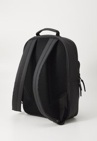 Schwarzer Rucksack mit gepolstertem, atmungsaktivem Rücken, verstellbaren Trägern und Reißverschlussdetails. Glattes Material mit einem eleganten, minimalistischen Design.