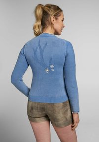 Blauer Strickcardigan mit einem strukturierten Zweigmuster und floralem Stickerei auf dem Rücken. Mit geripptem Saum und Ellbogenpatches.