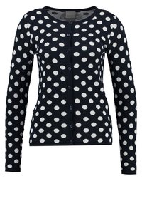 Navy cardigan with white polka dots, long sleeves, round neckline, button front closure, and soft knitted texture.