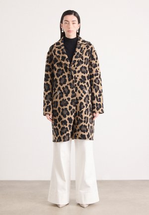 Leopardenmuster Wollmantel mit Reverskragen, schwarzen Knöpfen und seitlichen Reißverschlusstaschen, kombiniert mit hochgeschnittenen weißen Hosen.