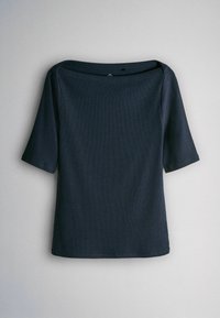 Tumši zila jūras krāsa ar platu kakla izgriezumu, trīs ceturtdaļu garuma piedurknēm un vienmērīgu ribotu tekstūru. Nav redzami nekādi raksti vai uzsvari.